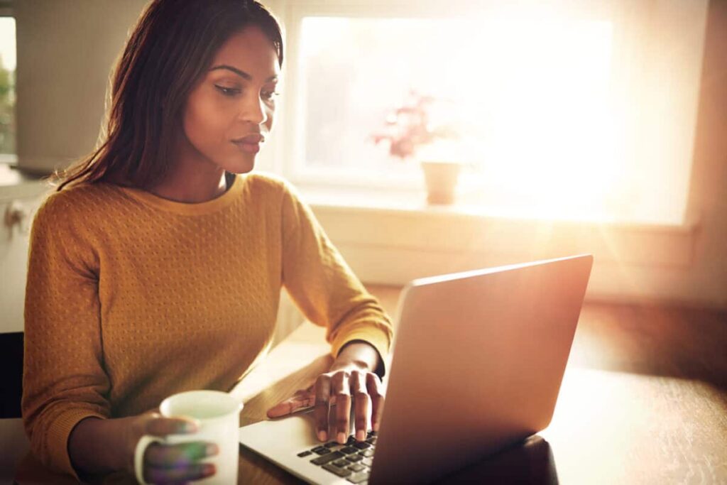 Use a TFSA to Make $800 in Monthly Tax-Free Income Woman checking her computer and holding coffee cup